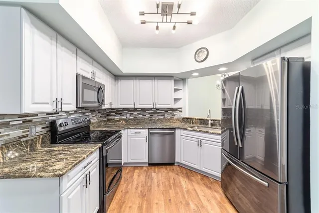 a kitchen with a refrigerator a sink and wooden floor