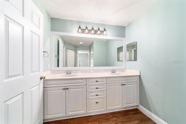 a view of a hallway with wooden floor and a bathroom