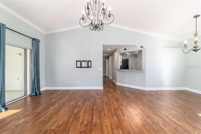a view of a hallway with wooden floor and a chandelier