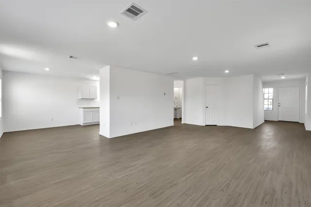 an empty room with wooden floor and windows