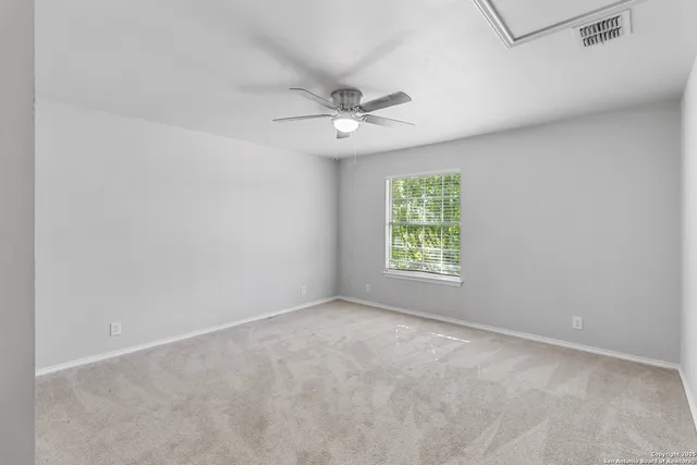 an empty room with windows and ceiling fan