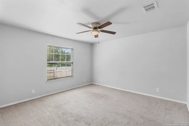 an empty room with windows and fan