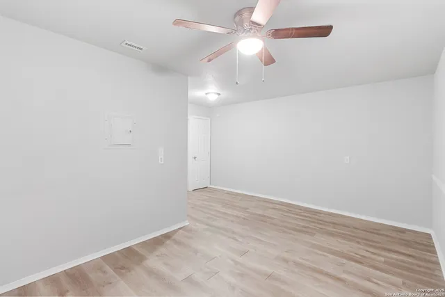 an empty room with a fan & a ceiling fan