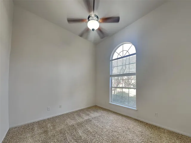 an empty room with windows and chandelier fan