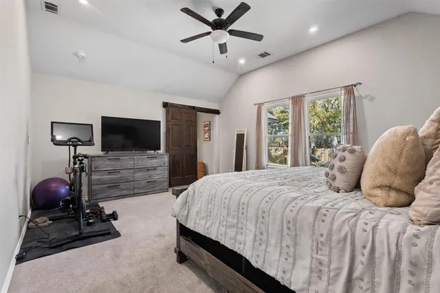 a bedroom with a bed and a flat tv screen on the dresser