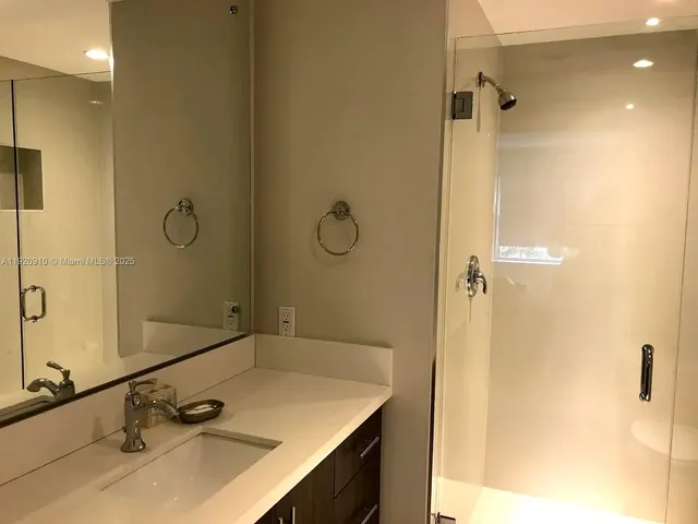 a bathroom with a sink vanity granite tub shower and a mirror