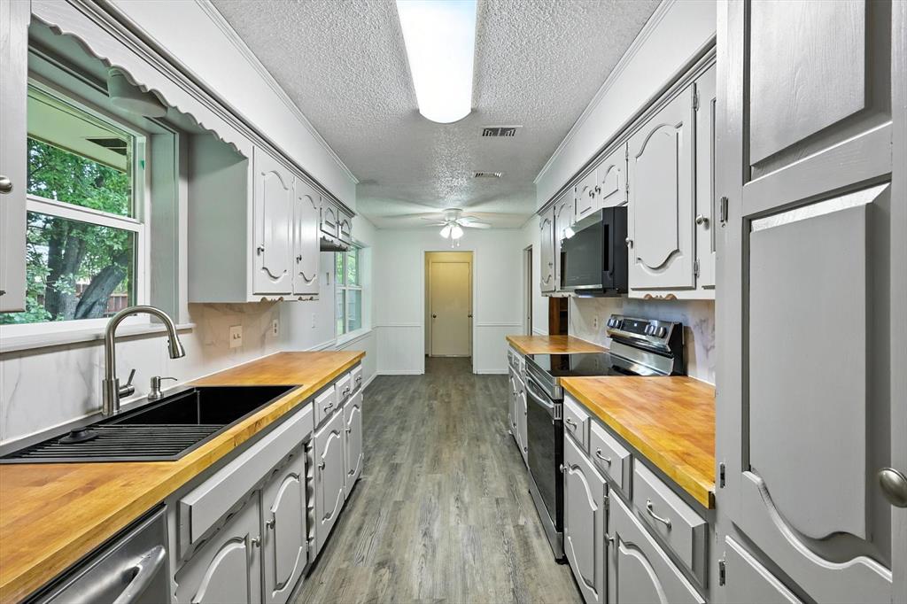 3300 Dunes Street Denton, TX 76209 - Photo 12 of 40 a kitchen with stainless steel appliances granite countertop lots of counter top space and wooden floor