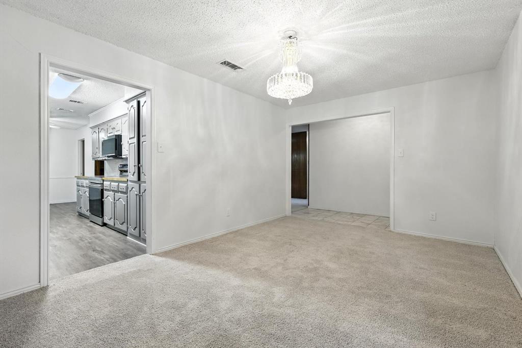 3300 Dunes Street Denton, TX 76209 - Photo 10 of 40 an empty room with kitchen view and wooden floor