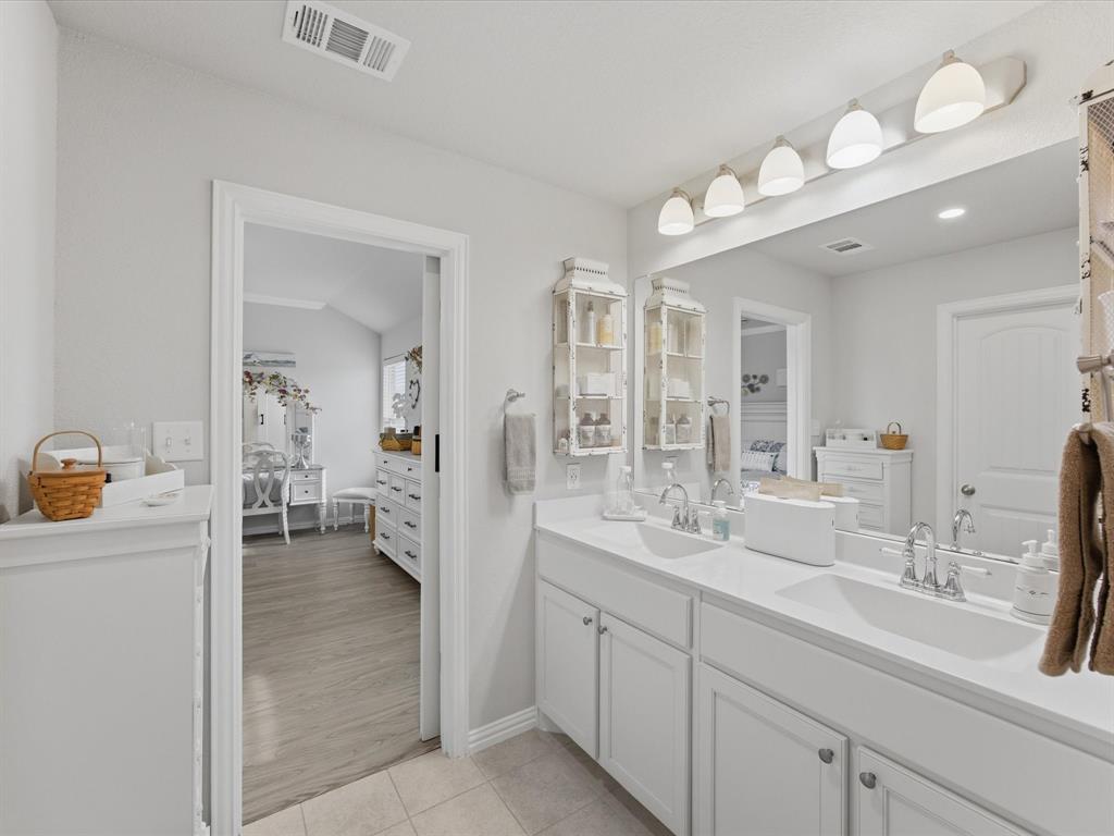 129 Springwood Ranch Loop Springtown, TX 76082 - Photo 20 of 26 Double vanity with white cabinetry and integrated sinks, complemented by a large mirror and multi-bulb vanity lighting