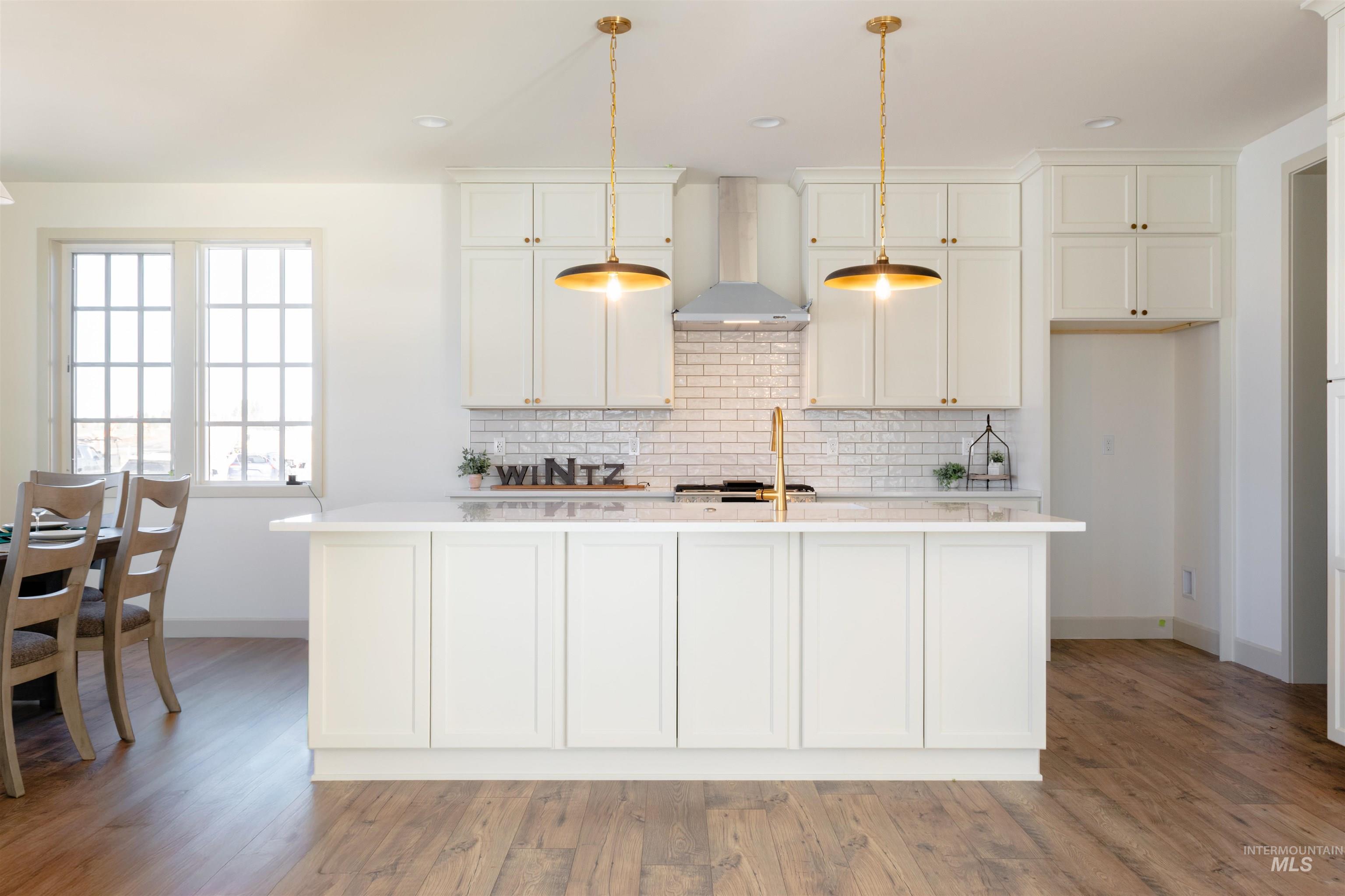 1560 Slonaker, Unit ONYX Moscow, ID 83843 - Photo 15 of 43 Kitchen with an island with sink, hanging light fixtures, light stone counters, white cabinetry, and light wood finished floors