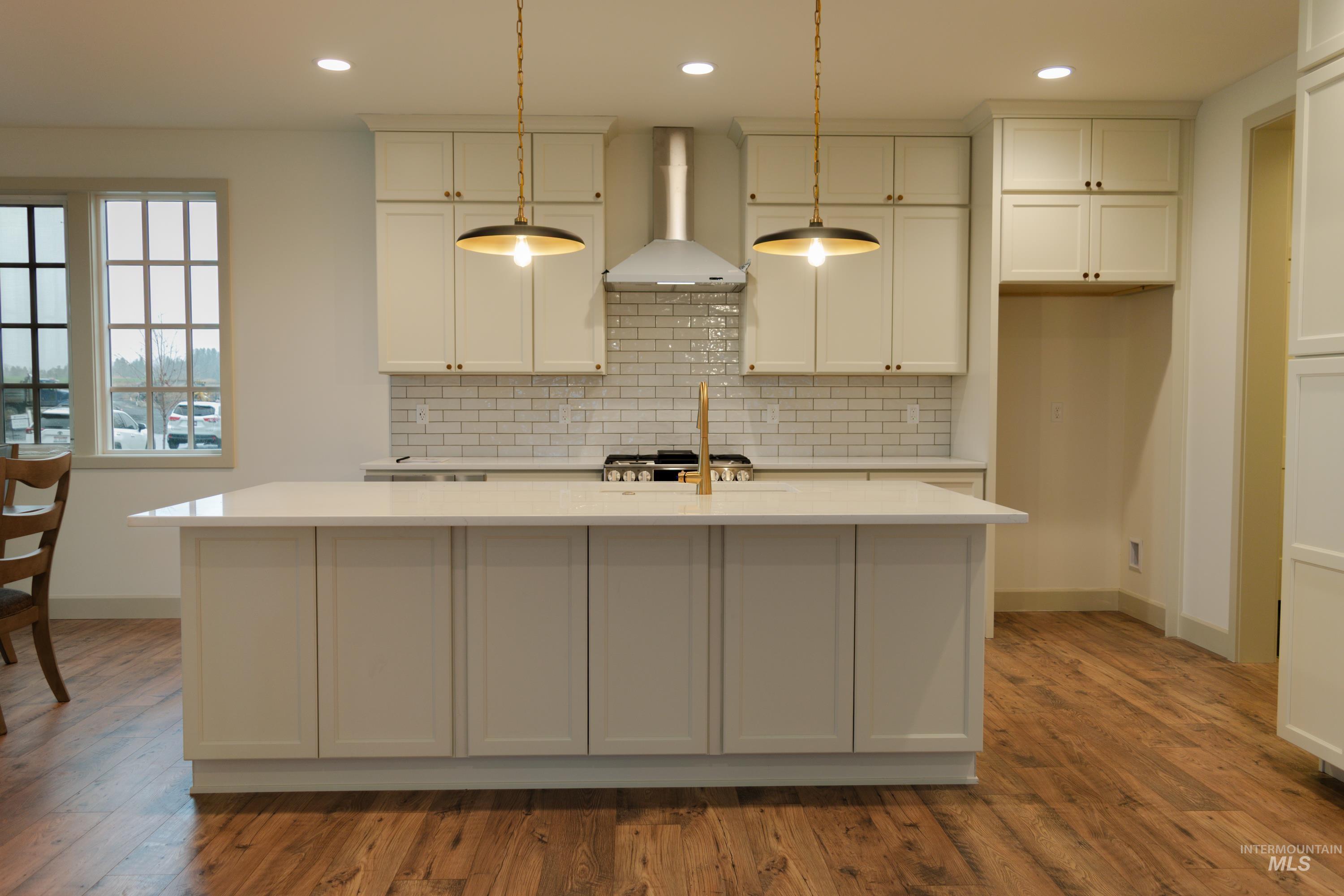 1560 Slonaker, Unit ONYX Moscow, ID 83843 - Photo 9 of 49 Kitchen with wall chimney exhaust hood, pendant lighting, recessed lighting, backsplash, and a kitchen island with sink