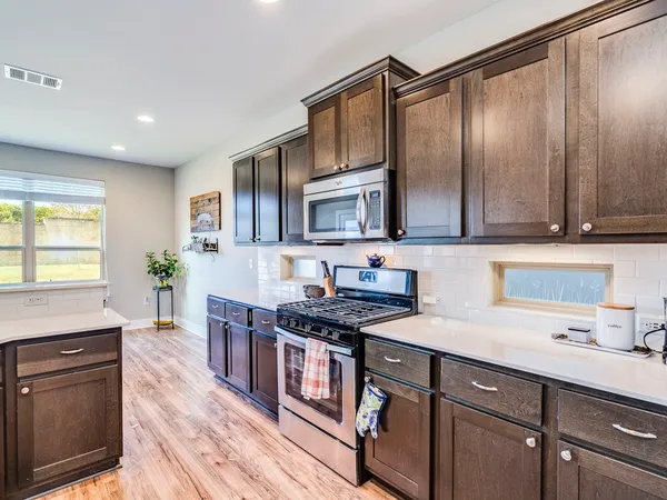a kitchen with stainless steel appliances granite countertop a stove a sink and a microwave