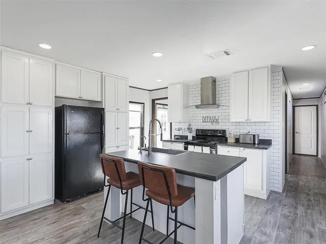 a kitchen with kitchen island granite countertop a sink cabinets and refrigerator