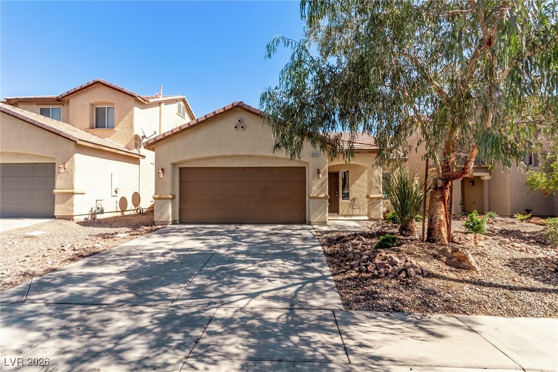 Mediterranean / spanish house with a tiled roof, stucco siding, driveway, and a garage
