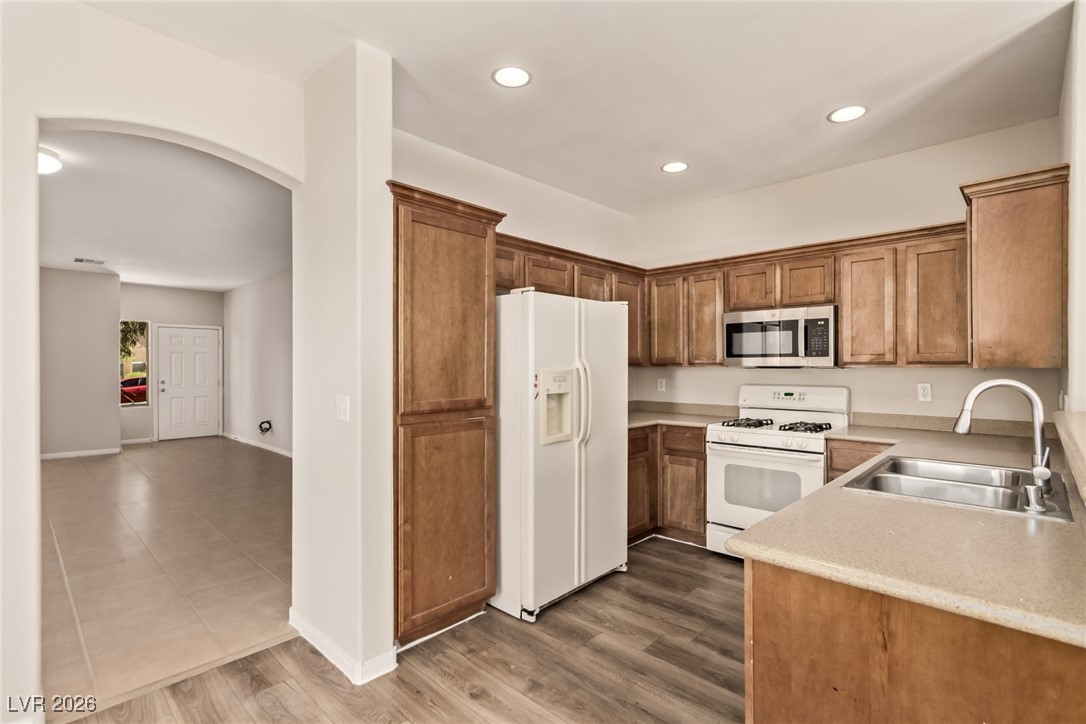 6224 Boulder Rise Street North Las Vegas, NV 89115 - Photo 12 of 27 Kitchen with arched walkways, white appliances, brown cabinets, recessed lighting, and dark wood-type flooring