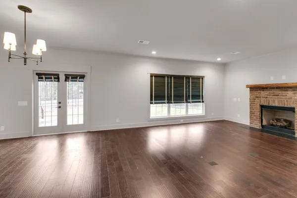 a view of an empty room with wooden floor fireplace and a window