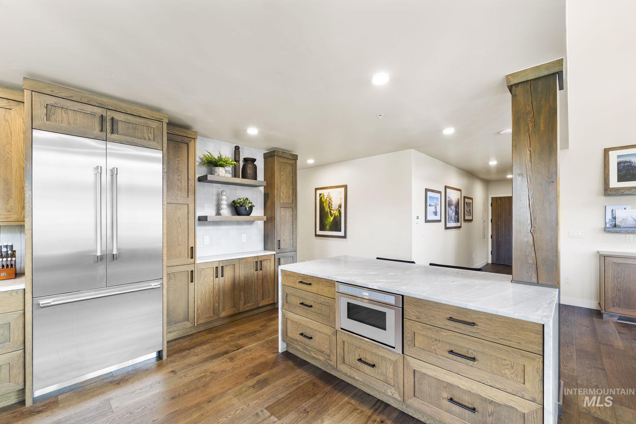 700 Village Drive, Unit 403 Donnelly, ID 83615 - Photo 14 of 43 Kitchen featuring stainless steel built in fridge, open shelves, light stone counters, brown cabinets, and dark wood-style floors