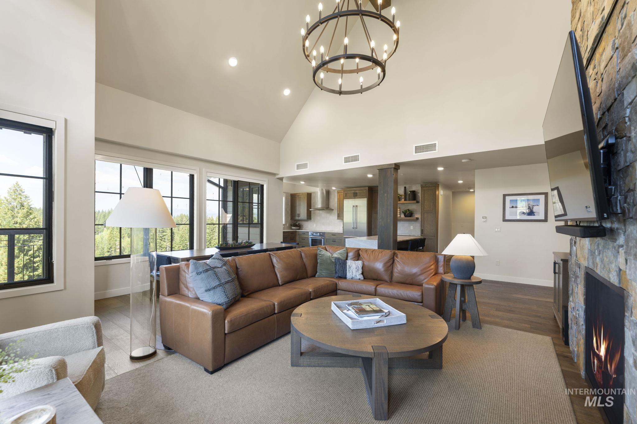 700 Village Drive, Unit 403 Donnelly, ID 83615 - Photo 9 of 43 Living room with wood finished floors, high vaulted ceiling, a chandelier, a stone fireplace, and recessed lighting