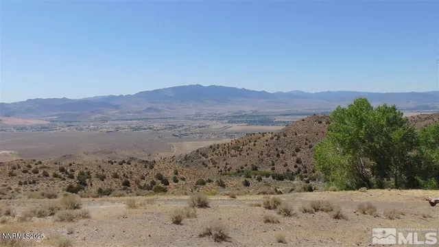 a view of a dry field with mountains in the background