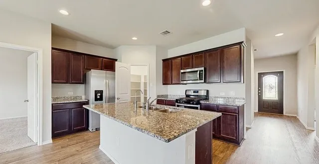 a kitchen with stainless steel appliances granite countertop a sink stove and refrigerator