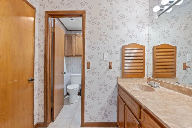 a bathroom with a granite countertop sink and a toilet