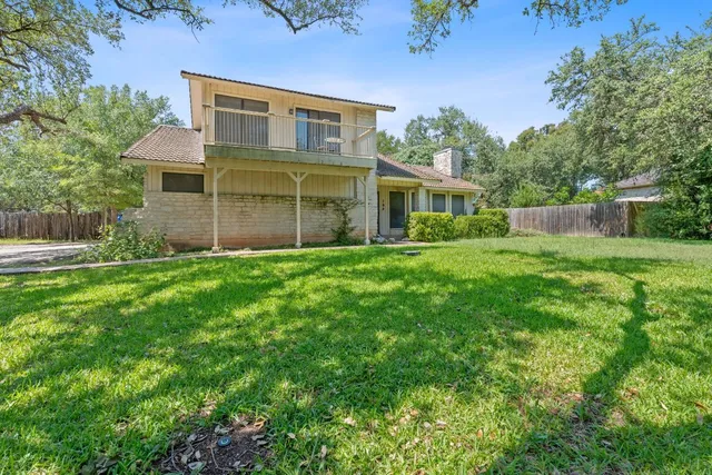 a view of a yard in front of a house with large tree