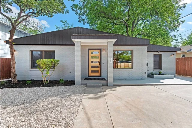 a front view of a house with a garden and a tree