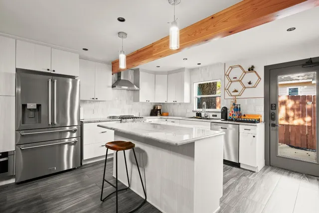 a kitchen with stainless steel appliances granite countertop a refrigerator and a stove top oven