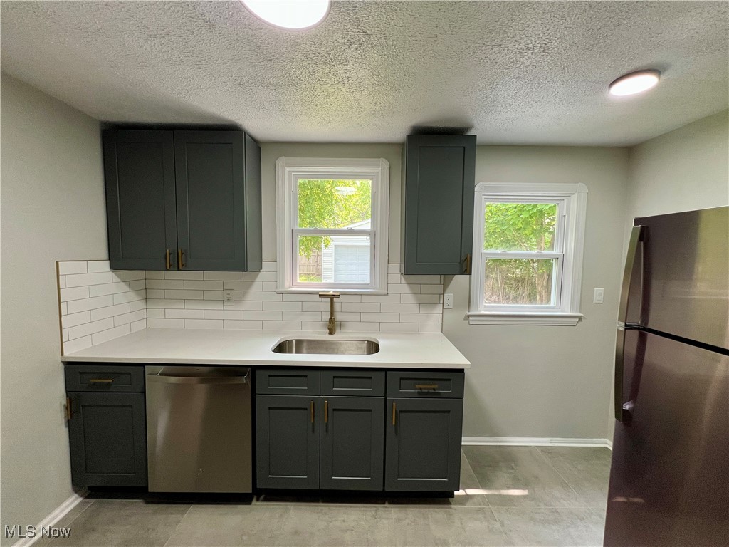 887 Yellowstone Road Cleveland Heights, OH 44121 - Photo 10 of 35 Kitchen featuring stainless steel appliances, a sink, light countertops, tasteful backsplash, and a textured ceiling