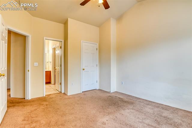 2049 Legacy Ridge View, Unit 111 Colorado Springs, CO 80910 - Photo 28 of 32 Unfurnished bedroom featuring light carpet, ensuite bath, vaulted ceiling, and ceiling fan