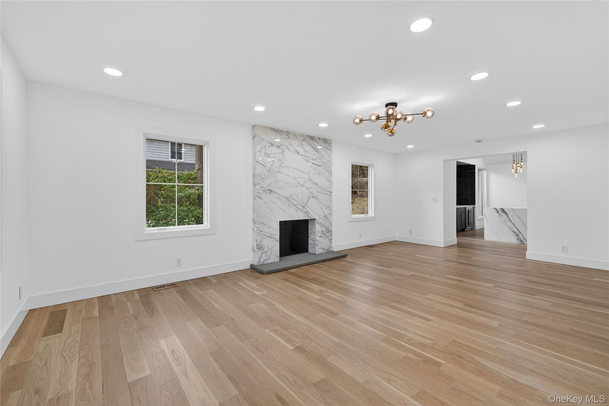 199 Salem Road East Hills, NY 11577 - Photo 12 of 40 Unfurnished living room featuring light wood finished floors, a chandelier, recessed lighting, and a high end fireplace