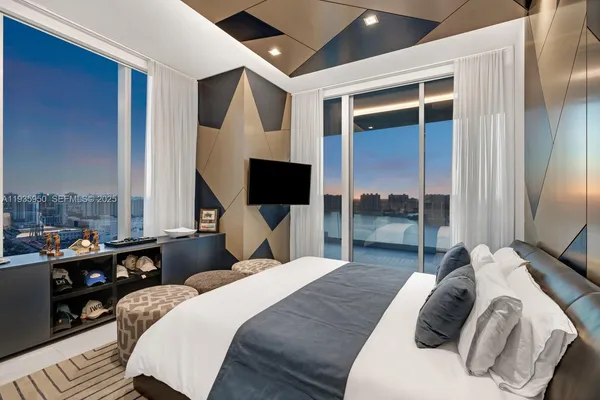 a bedroom with a bed a flat screen tv and a large window