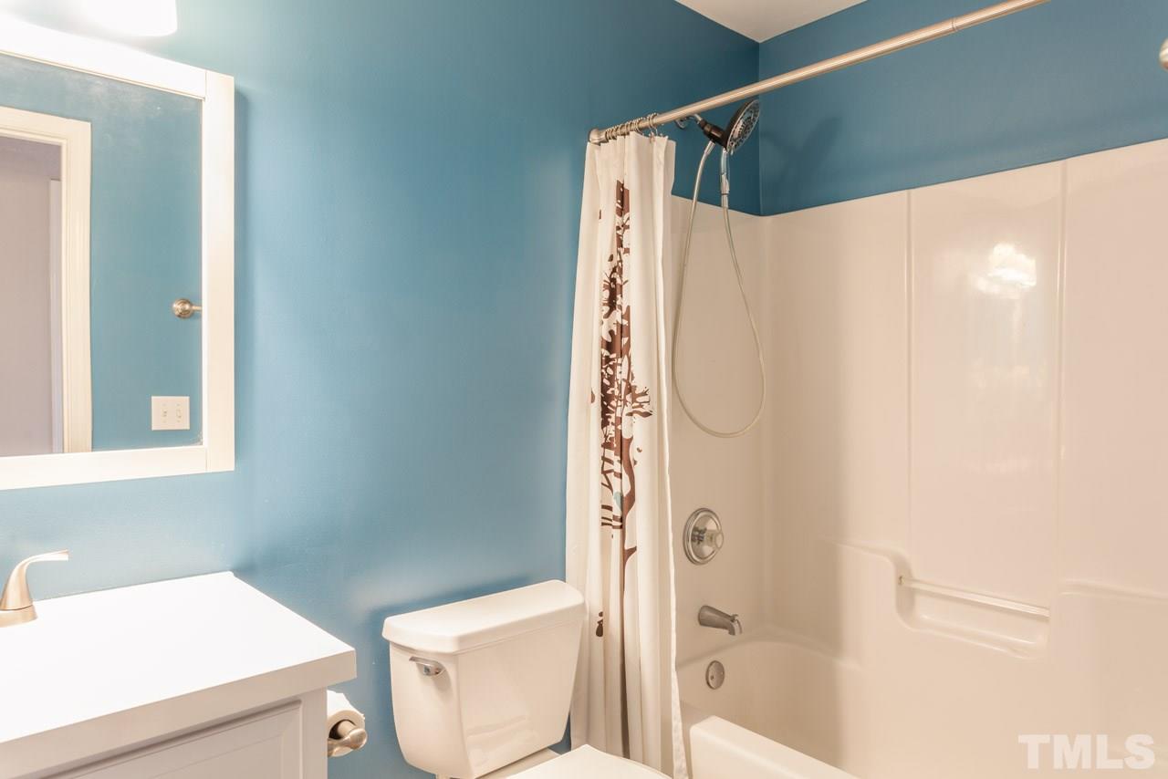 5216 Cardinal Grove Boulevard Raleigh, NC 27616 - Photo 19 of 25 a bathroom with a shower curtain and a toilet