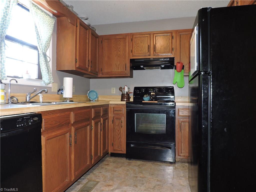7116 North River Road Oak Ridge, NC 27310 - Photo 6 of 22 Full suite of matching black appliances in the kitchen.