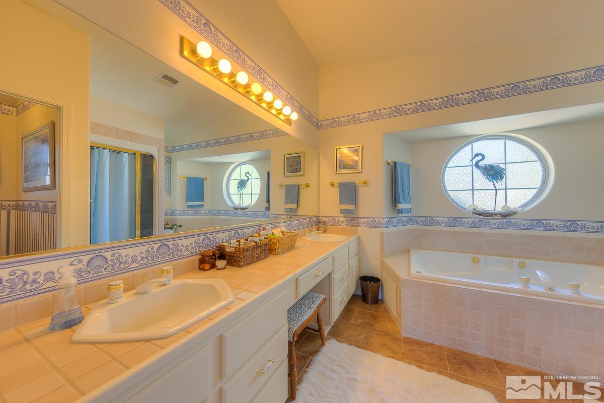 642 Talus Way Reno, NV 89503 - Photo 18 of 40 a bathroom with a tub a double vanity sink and a large mirror