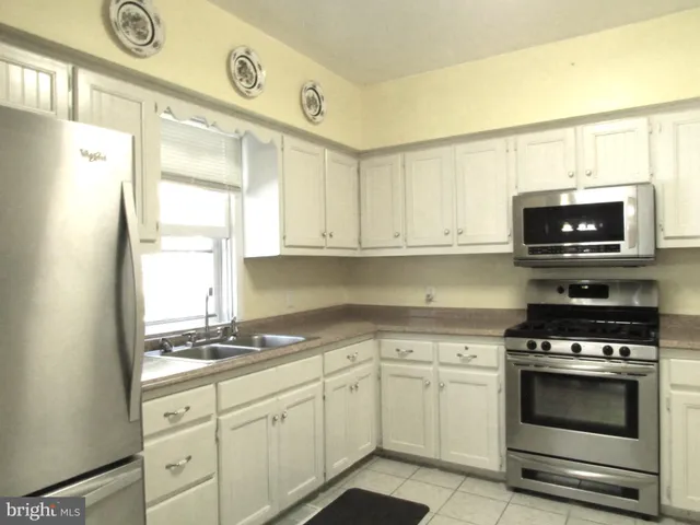a kitchen with granite countertop white cabinets stainless steel appliances and a window
