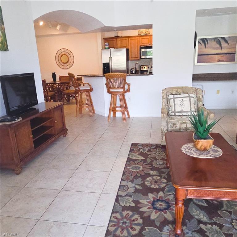 12975 Positano Circle, Unit 207 Naples, FL 34105 - Photo 2 of 24 Living room with arched walkways and light tile patterned floors