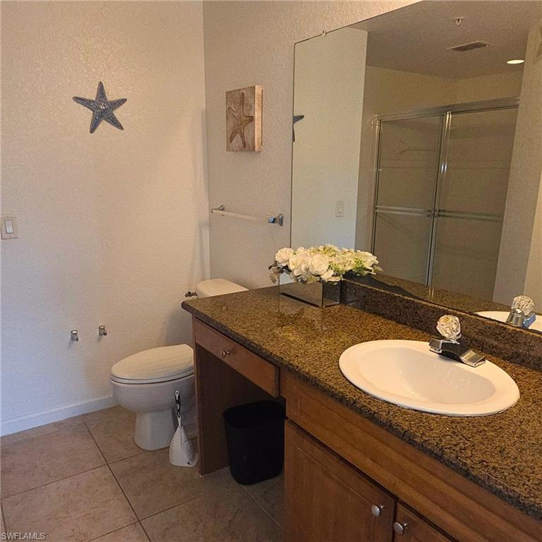12975 Positano Circle, Unit 207 Naples, FL 34105 - Photo 8 of 24 Full bathroom featuring vanity, a stall shower, light tile patterned floors, and a textured wall
