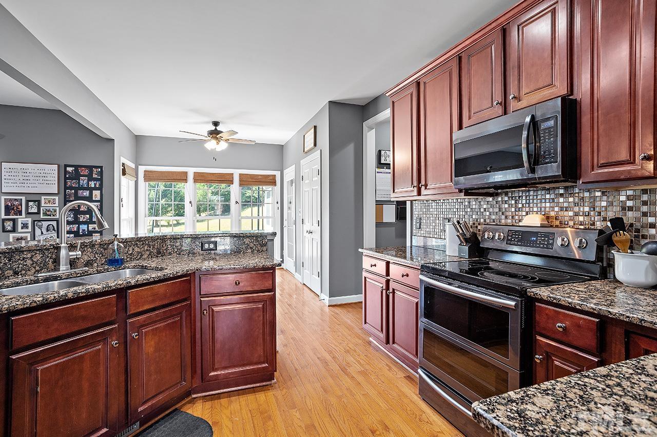 709 Rushing Falls Place Fuquay-Varina, NC 27526 - Photo 11 of 28 a kitchen with stainless steel appliances granite countertop wooden cabinets stove top oven and microwave