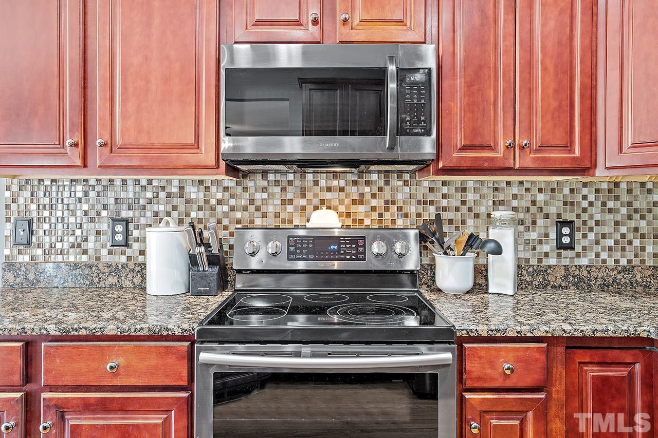 709 Rushing Falls Place Fuquay-Varina, NC 27526 - Photo 9 of 28 a kitchen with granite countertop a stove top oven microwave and cabinets