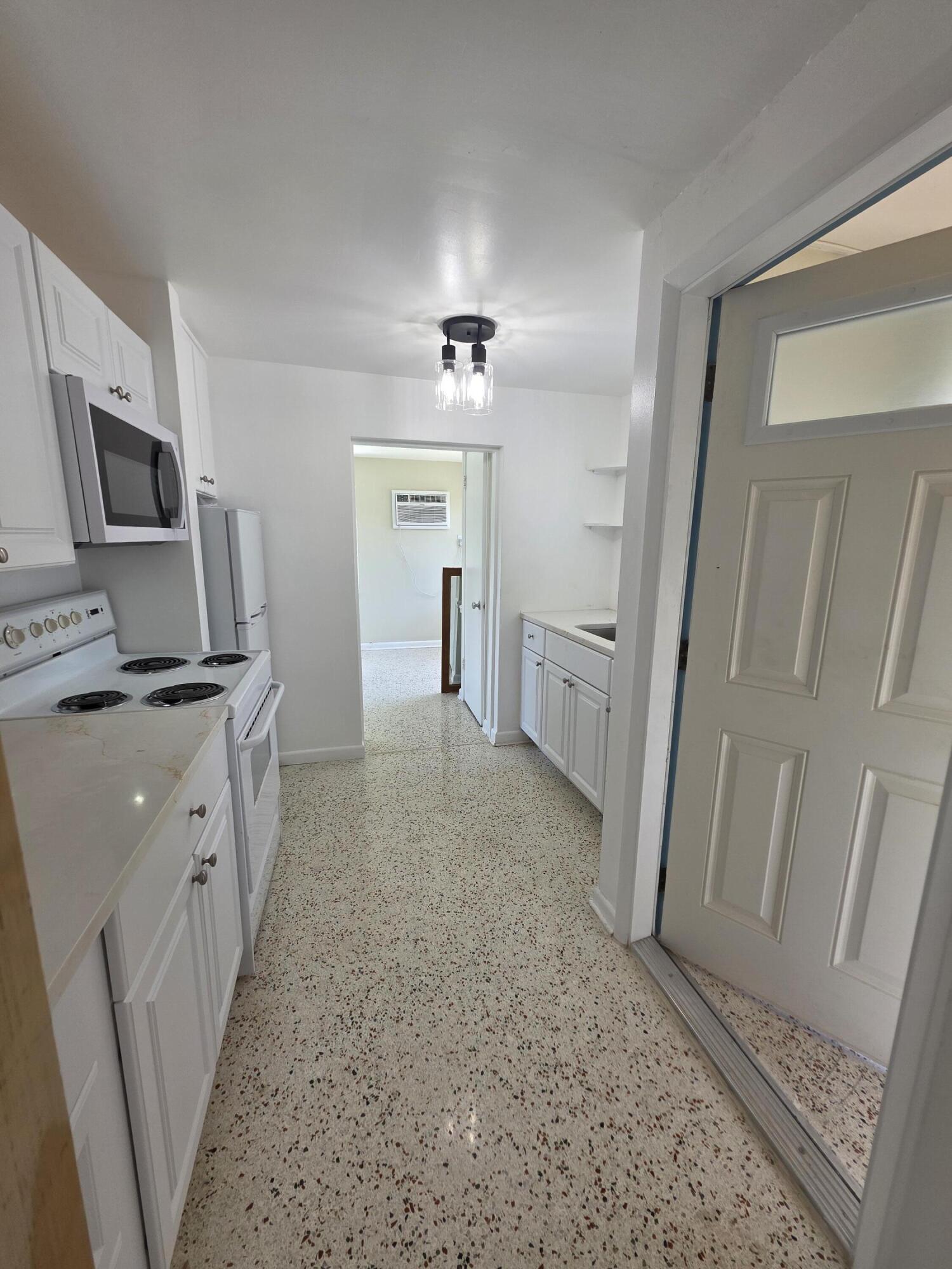 1216 Cabana Road, Unit 4 Singer Island, FL 33404 - Photo 2 of 10 a open kitchen with white cabinets and stainless steel appliances