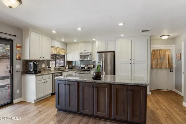 a kitchen with stainless steel appliances granite countertop a stove a refrigerator a sink dishwasher and a refrigerator with wooden floor