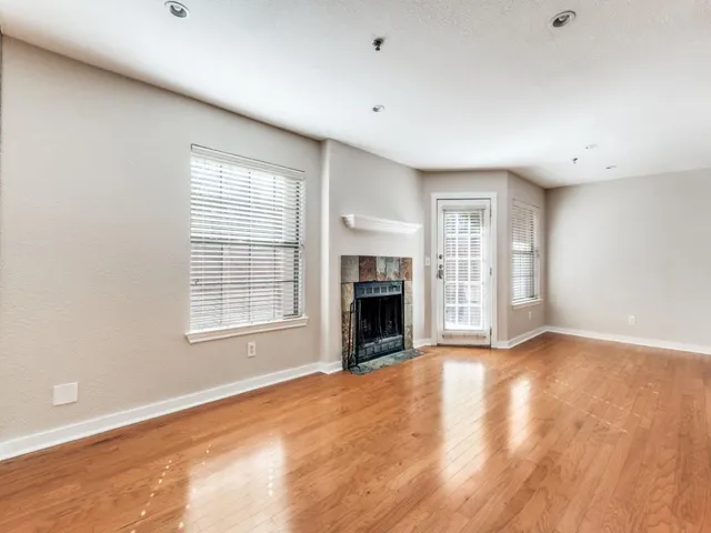 an empty room with windows a fireplace and wooden floor