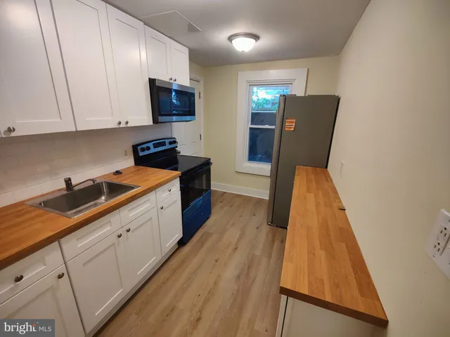 a kitchen with sink a microwave a refrigerator and cabinets
