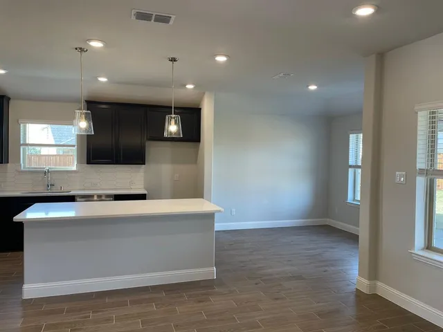 a large kitchen with stainless steel appliances a large counter top and a wooden floors