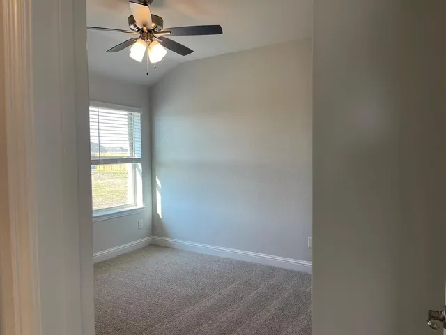 an empty room with windows and fan