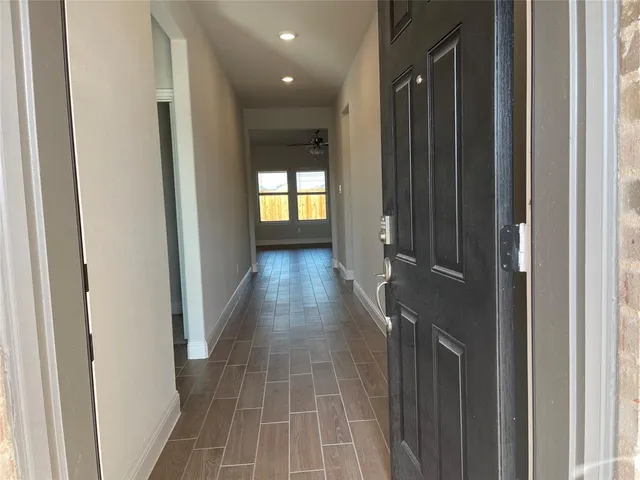 a view of a hallway with wooden floor and a bathroom