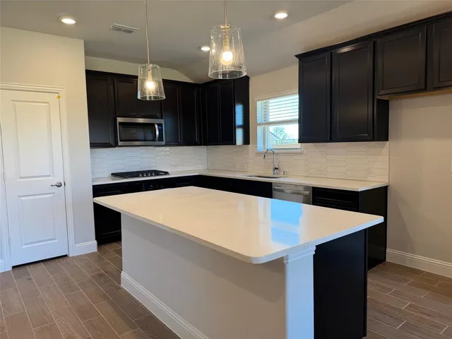 a kitchen with kitchen island granite countertop wooden cabinets and a refrigerator