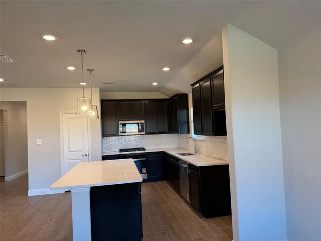 a kitchen with stainless steel appliances kitchen island granite countertop a refrigerator and a sink