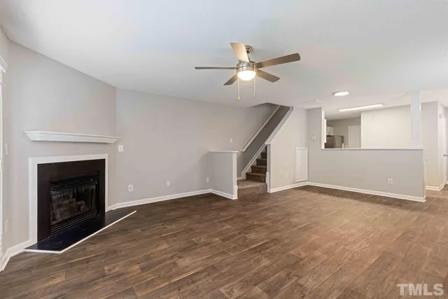 a view of an empty room with wooden floor a fireplace